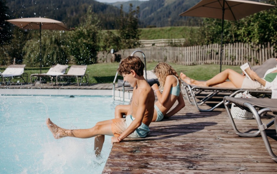Eltern entspannen auf Liegest&uuml;hlen am Pool, Kinder spielen im Pool vom Hotel Resl