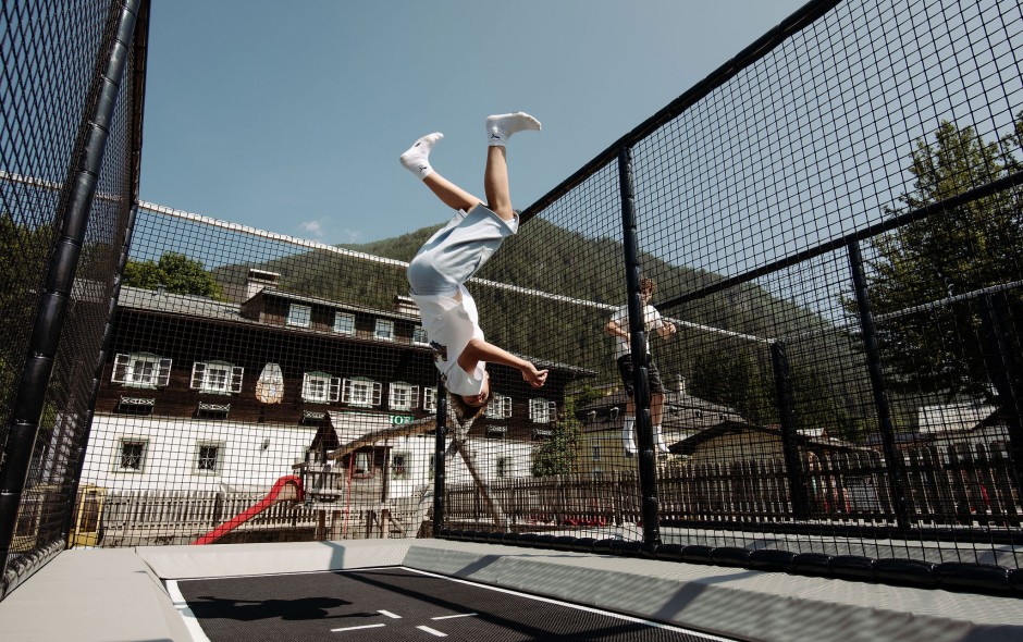 Familienfreundliche Trampolinanlage im Freien, auf der Kinder aktiv Spa&szlig; haben mit Blick auf die Berge