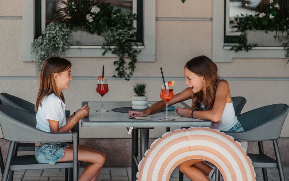 Zwei M&auml;dchen spielen Karte und schl&uuml;rfen einen Kinder-Cocktail