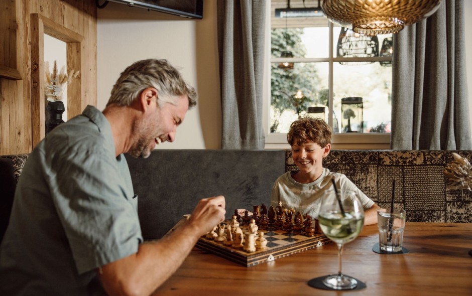 Vater und Sohn spielen Schach im gem&uuml;tlichen Restaurantbereich des Hotel Resl Resort in Flachau